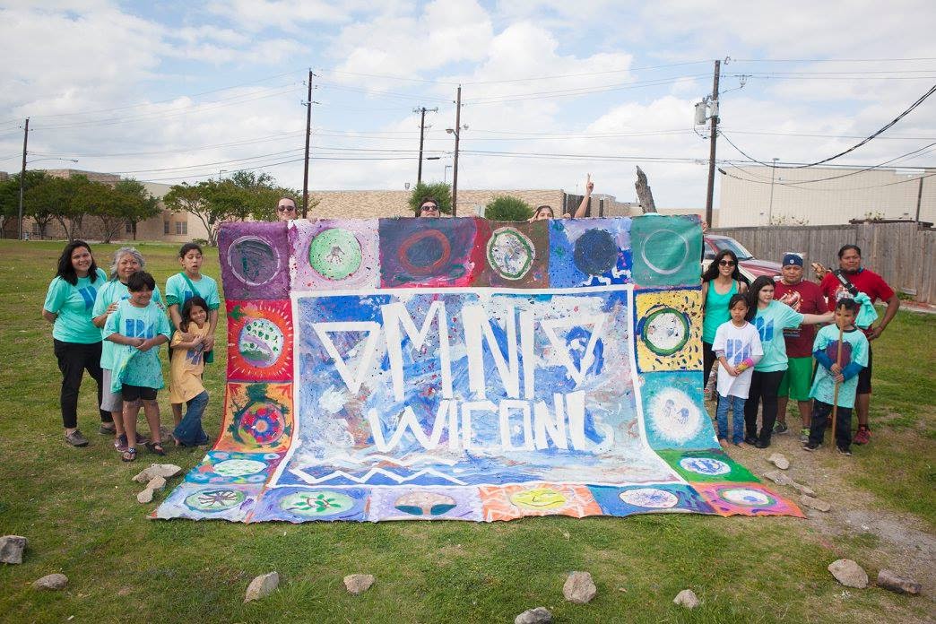 Artists and community members standing with a colorful collaborative artwork